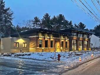 Winter view of  long, low building with snow and a fire hydrant in the foreground.  Building has three truck-sized doorways and one pedestrian-sized door. 