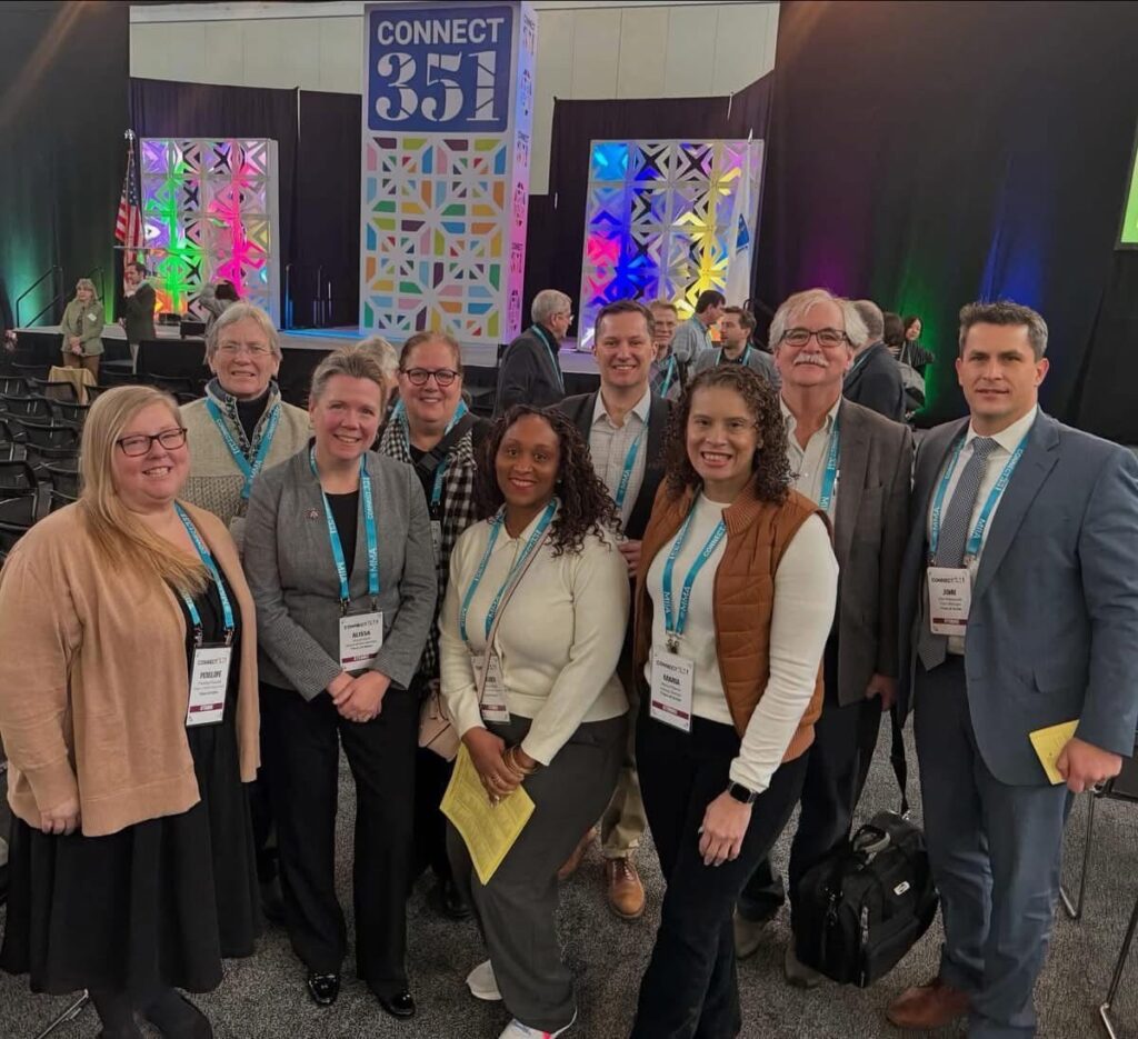 A group of people, all Acton employees or elected officials, stand under a Connect 351 sign.