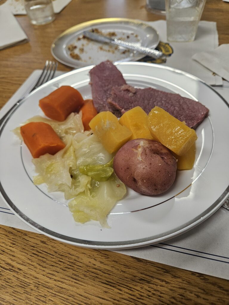 A plate of food with cabbage, corned beef, carrots, and potatoes.