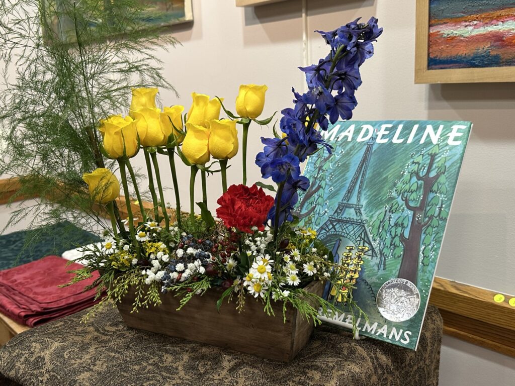 A display with yellow roses, daisies, and blue and red flowers that looks like a formal park garden.