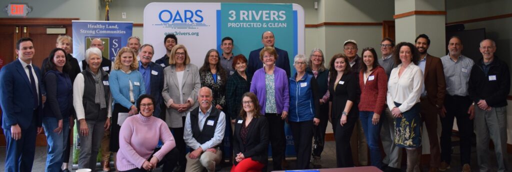 A group of people lined up in front o signs that say OARS and 3 Rivers.